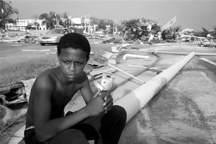 A young man sitting in the aftermath of Hurricane Katrina